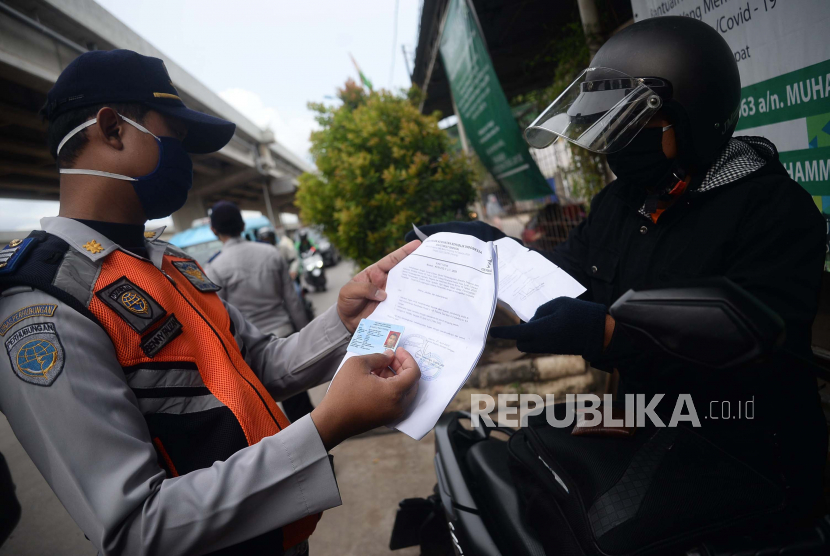 Petugas melakukan pengecekan dokumen kepada pengendara dengan plat nomor luar daerah yang melintasi Check Point PSBB di kawasan Kalimalang, Jakarta, Selasa (26/5). Pemerintah Provinsi DKI Jakarta menerapkan aturan penggunaan Surat Izin Keluar-Masuk (SIKM) untuk membatasi warga yang keluar masuk Jakarta pada masa arus balik