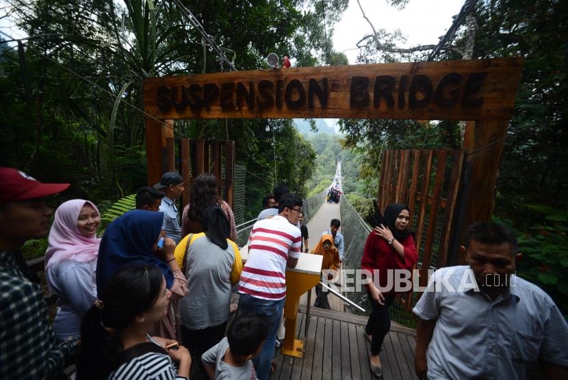 Wisatawan antre untuk melintasi  Situ Gunung Suspension Bridge di Taman Nasional Gunung Gede Pangrango, Kadudampit, Sukabumi.