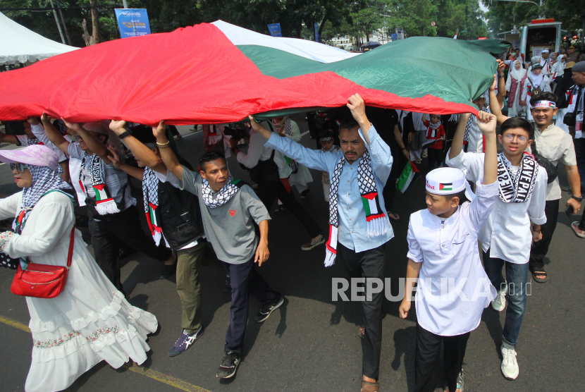 Peserta aksi membawa bendera Palestina raksasa saat aksi solidaritas untuk Palestina di depan Gedung Sate, Kota Bandung, Jawa Barat, Jumat (17/11/2023). 