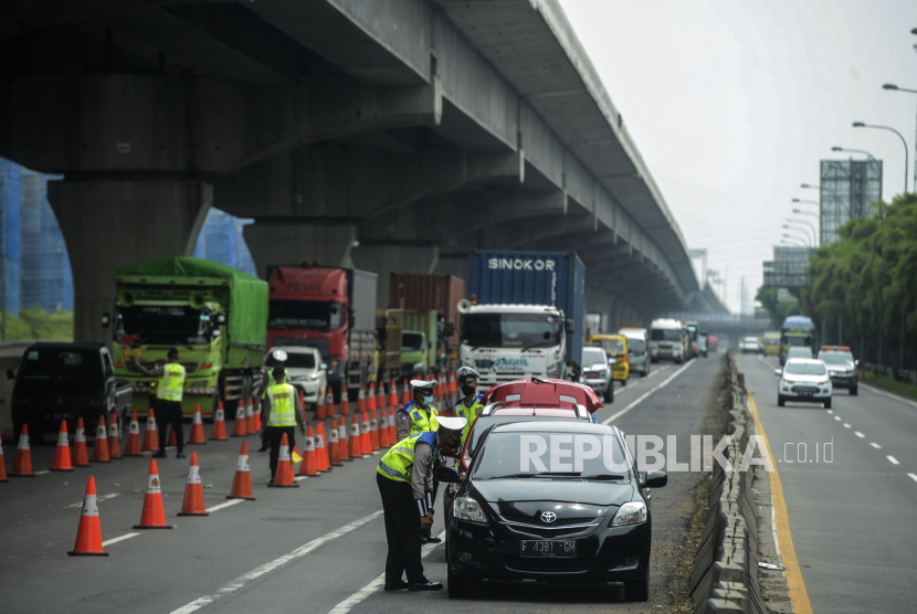 Sejumlah polisi melakukan penyekatan saat menerapkan pelarangan mudik di tol Jakarta-Cikampek, Cikarang, Kabupaten Bekasi, Jawa Barat, Sabtu, (25/4). Hari kedua penerapan pelarangan mudik di akses tol Jakarta - Cikampek masih banyak pengendara yang memaksakan untuk mudik dan tidak menerapkan jarak sosial