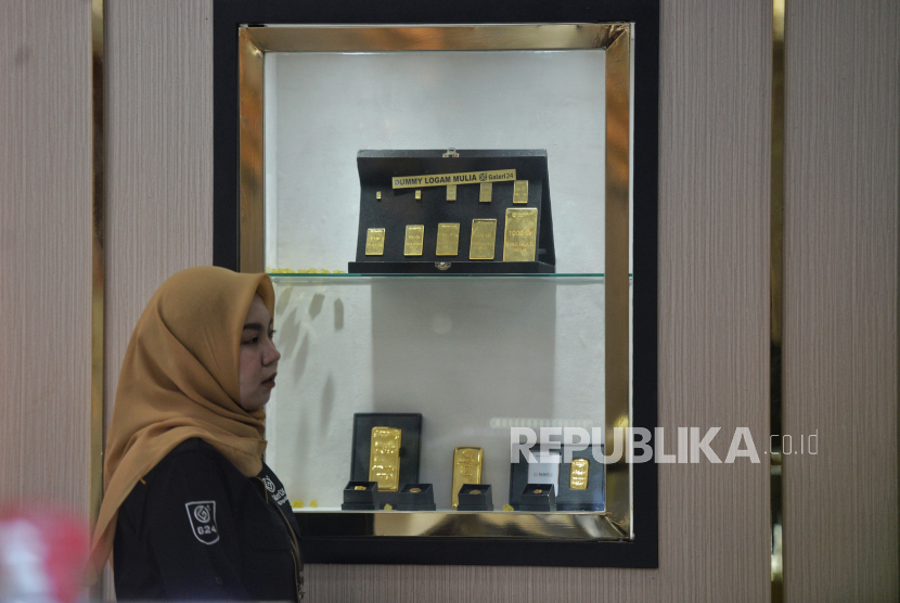 Karyawan melintas didekat koleksi emas di Galeri24 Pegadaian, Jakarta Selasa (11/1/2022). 