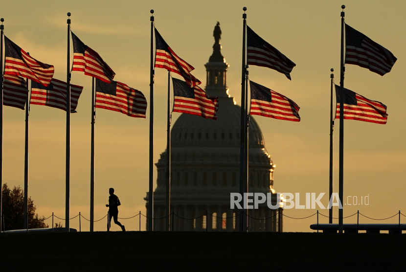  Seorang pelari melewati bendera AS di National Mall di depan Gedung Capitol di Washington, DC, AS, 8 Oktober 2022. Indeks harga konsumen (IHK) di Amerika Serikat akhirnya mencetak deflasi secara bulanan pertama kali sejak dua setengah tahun lalu.