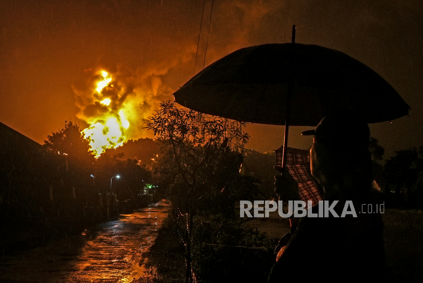 Warga menonton kobaran api yang terlihat di Kilang Pertamina Internasional (KPI) RU IV Cilacap, Jawa Tengah, Ahad (14/11/2021) dini hari. Tangki 36 T 102 terbakar pada Sabtu (13/11/2021) pukul 19.10 WIB itu berisi komponen pertalite. 
