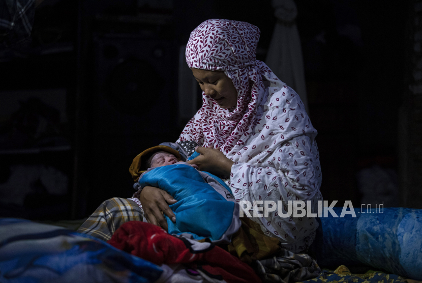 Pengungsi korban gempa, Kartini (26 tahun) menggendong anaknya yang baru saja ia lahirkan di kawasan Stadion Manakarra, Mamuju, Sulawesi Barat, Selasa (19/1/2021).