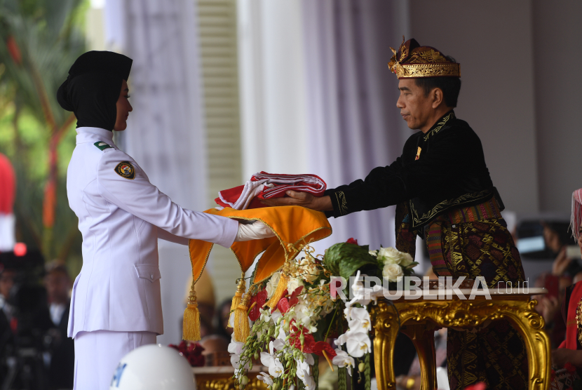 Presiden Joko Widodo memberikan bendera kepada pembawa baki Paskibraka  berjilbab pada upacara Kemerdekaan Indonesia ke-74 Tahun 2019 di Istana Merdeka, Jakarta, Sabtu (17/8/2019). 