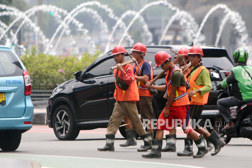 Pekerja konstruksi berjalan melintasi jalan utama di Jakarta, Indonesia, 28 November 2022. Kamar Dagang dan Industri (Kadin) Indonesia siap memenuhi kebutuhan tenaga kerja sektor konstruksi yang dibutuhkan Malaysia.
