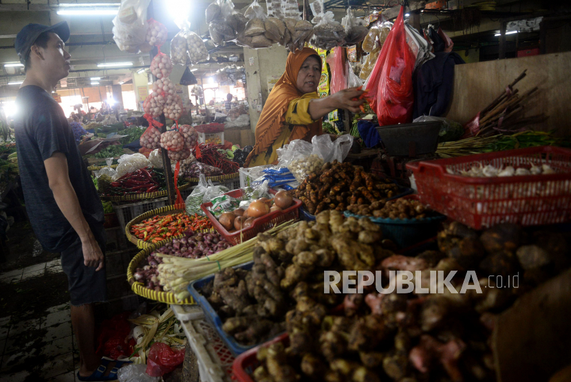Pedagang sayur mayur melayani pembeli di pasar tradisional.