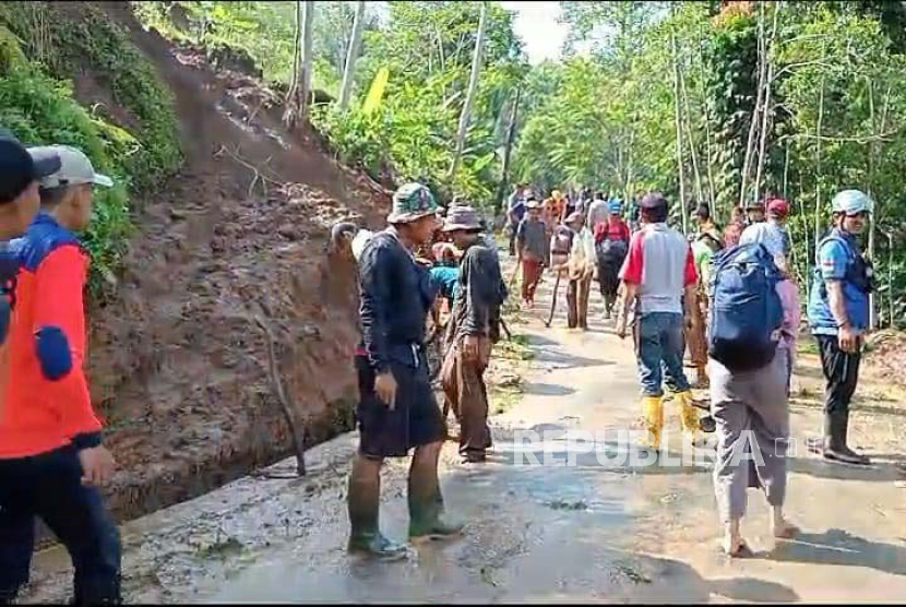Petugas dan warga berupaya membuka akses jalan yang tertutup tanah longsor di Kecamatan Cigalontang, Kabupaten Tasikmalaya, Ahad (7/1/2024).  