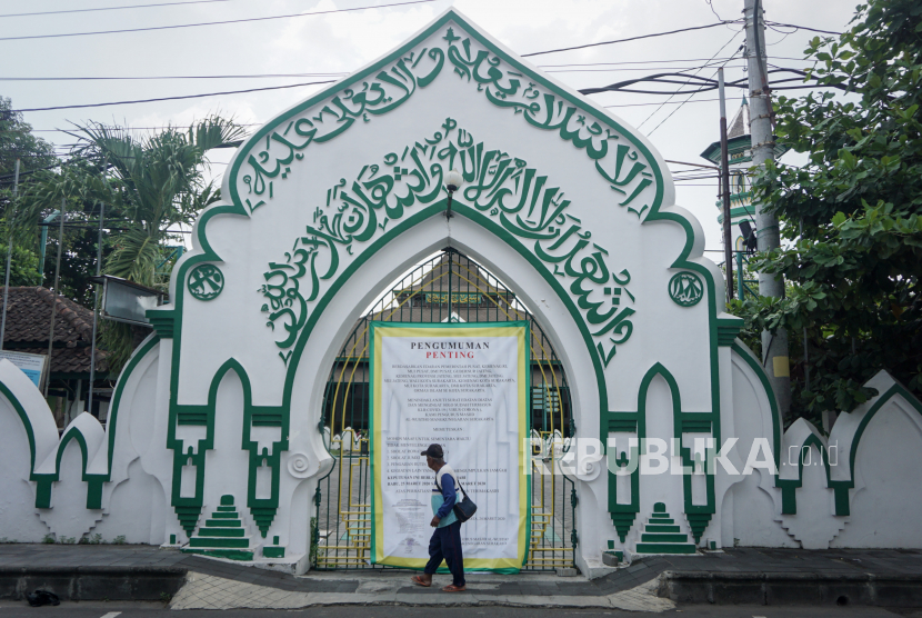 Warga melintas didepan pemberitahuan ditiadakan Shalat Jumat di Masjid Al Wusto, Mangkunegaran, Solo, Jawa Tengah, Jumat (27/3/2020). 