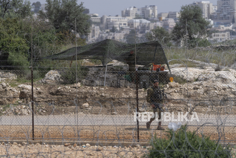  Raja Yordania: Israel Lakukan Tindakan Provokatif. Foto:  Seorang tentara Israel menjaga sebuah celah di pembatas pemisah Tepi Barat Israel yang diperkuat dengan kawat berduri untuk mencegah warga Palestina menyeberang ke Israel, di desa Nilin, Tepi Barat, barat Ramallah, 10 April 2022. 