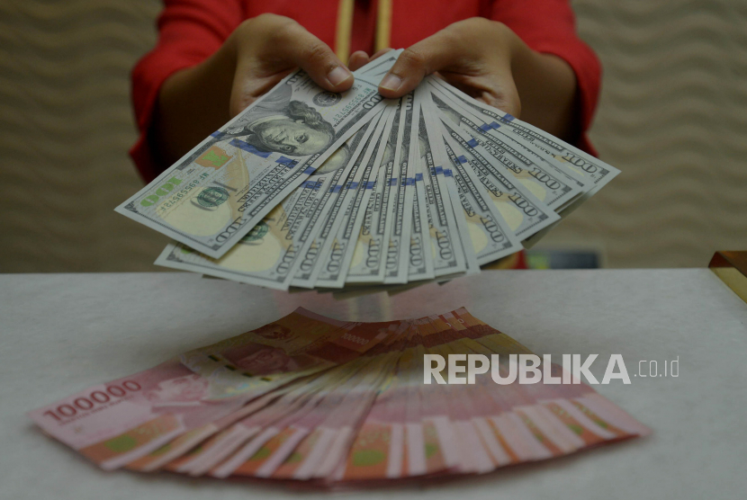 Petugas menunjukkan uang rupiah dan dolar AS di salah satu gerai penukaran mata uang asing di Jakarta, Kamis (29/9/2022). Nilai tukar rupiah terhadap dolar Amerika Serikat (AS) ditutup menguat pada penutupan perdagangan Kamis (29/9/2022) sebesar 4 poin atau 0,03 persen ke level Rp15.262,50 per dolar AS.  