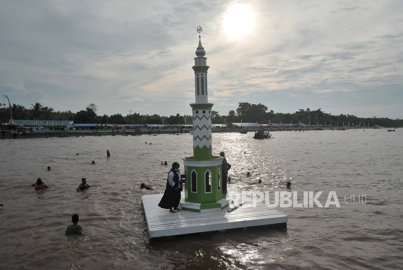 Warga menaiki menara adat yang ditarik menggunakan kapal motor menjelang Tradisi Mandi Safar 2022 di perairan Air Hitam Laut, Tanjungjabung Timur, Jambi. Naskah Khutbah Jumat: Bulan Safar Hapus Mitos 