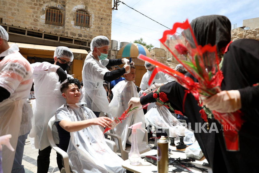 Sekelompok penata rambut Palestina mengenakan masker kampanye potong rambut gratis untuk warga Palestina di Tepi Barat, Hebron, Palestina, Senin (11/5). Palestina memutuskan untuk melonggarkan lockdown di Tepi Barat. Ilustrasi.