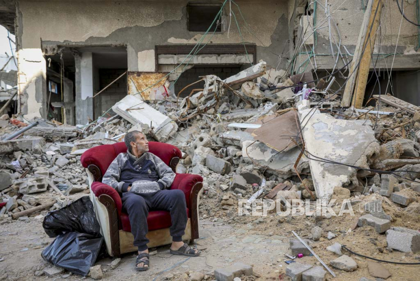 Seorang pria Palestina duduk di kursi berlengan di luar bangunan yang hancur di Kota Gaza pada Rabu, 29 November 2023, hari keenam gencatan senjata sementara antara Hamas dan Israel. 
