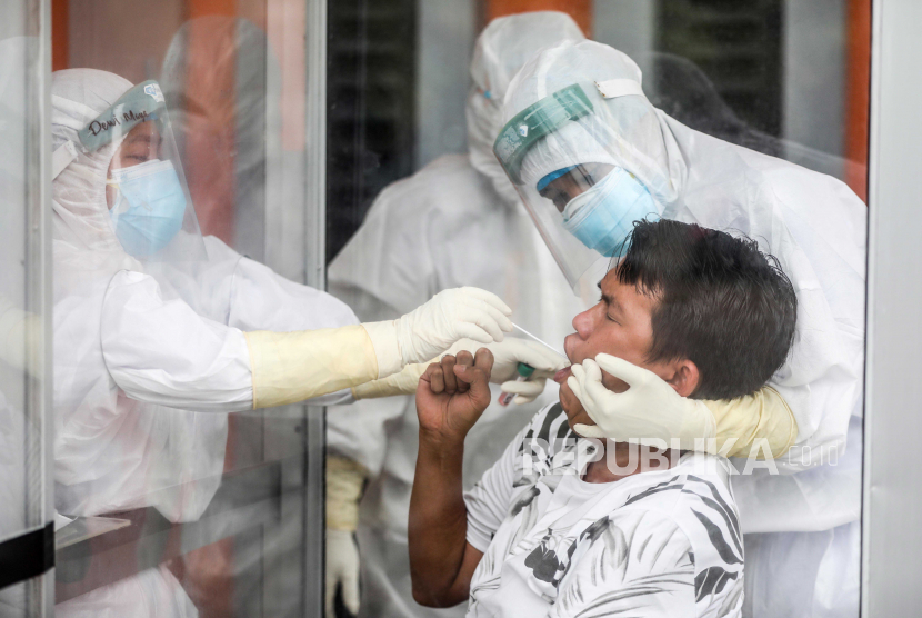  Petugas kesehatan dengan pakaian hazmat mengumpulkan sampel spesimen melalui kaca plexiglass selama uji coba swab COVID-19 di Medan, Sumatera Utara, Indonesia, 01 Desember 2020.