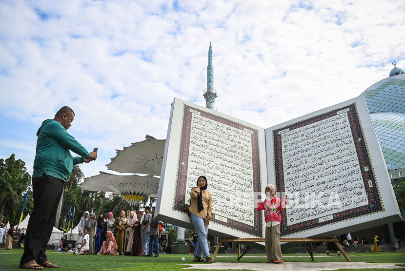 Sejumlah warga berpose di depan replika Al-Quran raksasa di halaman Masjid Al-Adzom, Kota Tangerang, Banten, Ahad (7/7/2024). Pemerintah Kota Tangerang menghadirkan replika Al-Quran raksasa setinggi 4 meter untuk memeriahkan Festival Al-Adzom dalam rangka memperingati tahun baru Islam  Muharram 1446 Hijriah. 