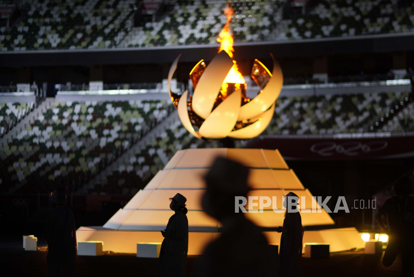 Relawan berdiri saat Presiden Komite Olimpiade Internasional Thomas Bach memberikan pidato pada upacara penutupan di Stadion Olimpiade pada Olimpiade Musim Panas 2020, Minggu, 8 Agustus 2021, di Tokyo, Jepang.