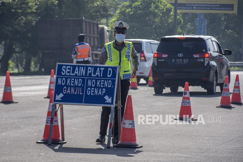 Petugas kepolisian mengatur lalu lintas saat pemberlakuan ganjil genap di gerbang keluar Tol Pasteur, Kota Bandung, Ahad (20/3/2022). 