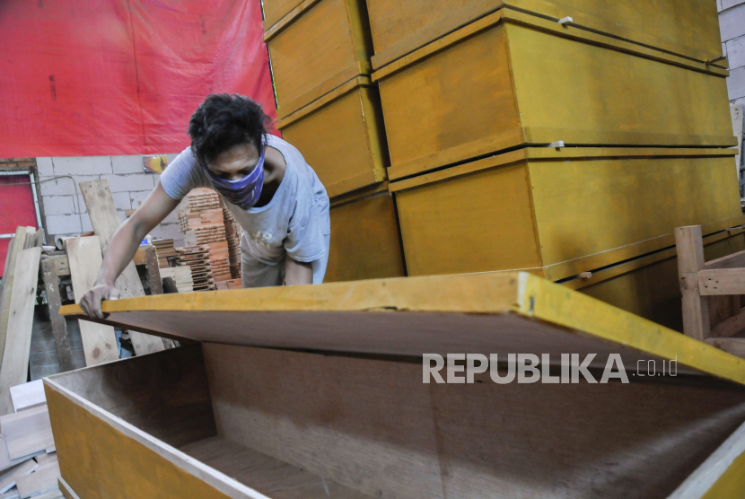 Pekerja menyelesaikan proses pembuatan peti jenazah di Tambun, Kabupaten Bekasi, Jawa Barat, (16/7/2021). Perajin mebel di daerah tersebut beralih membuat peti jenazah karena meningkatnya permintaan akibat wabah COVID-19 yang banyak menelan korna jiwa.