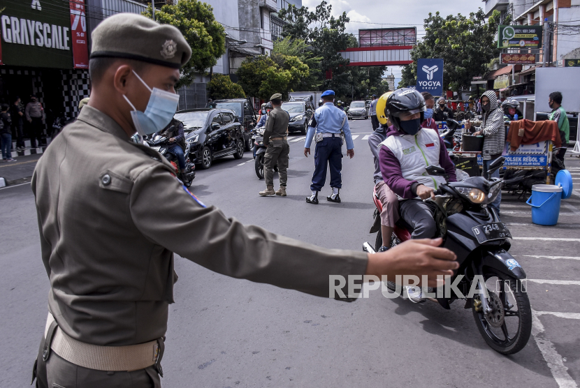 Petugas gabungan menghentikan pengendara yang tidak menggunakan masker saat operasi gabungan patroli pengawasan dan penegakan disiplin protokol kesehatan Covid-19 di Jalan Dalem Kaum, Kota Bandung, Kamis (31/12/2020). 