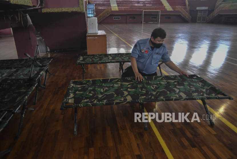 Petugas dinas sosial menyiapkan tempat tidur bagi warga yang terkena virus Covid-19 di salah satu GOR di Jakarta.