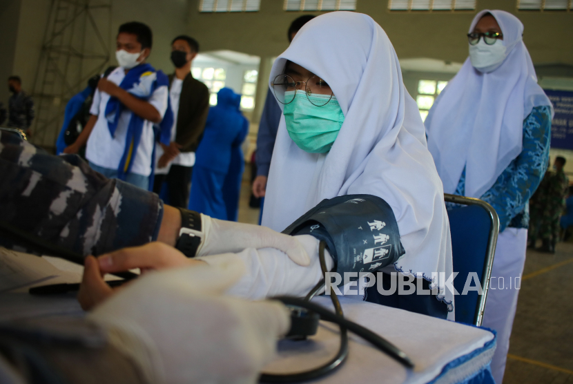 Petugas kesehatan memeriksa tekanan darah anak sebelum divaksin Covid-19 di GOR Basket Bumimoro, Surabaya, Jawa Timur, Selasa (24/8).