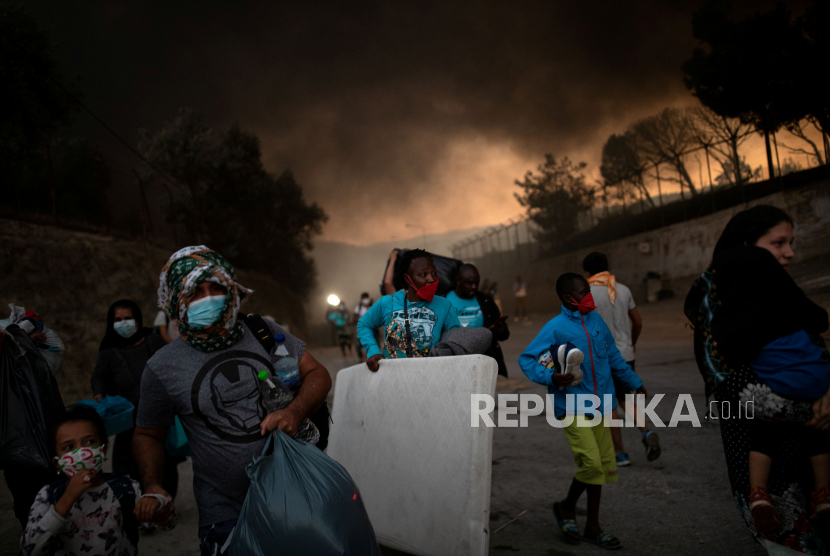  Pengungsi dan migran yang membawa barang-barangnya melarikan diri dari kebakaran yang terjadi di kamp Moria di pulau Lesbos, Yunani, 9 September 2020. 