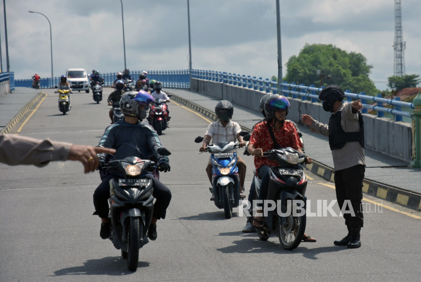 Riau akan Ajukan PSBB Menyeluruh. Sejumlah petugas polisi menghentikan pengendara motor yang tidak bermasker pada hari Pembatasan Sosial Berskala Besar (PSBB) di Kota Pekanbaru, Riau.