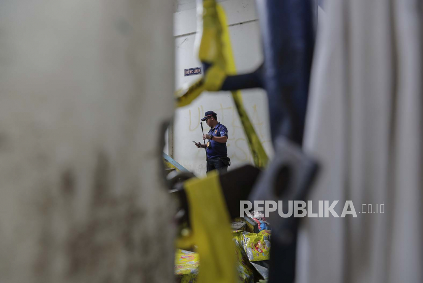 Petugas polisi forensik menyelidiki di dekat pintu masuk tribun gerbang 13, lokasi utama penyerbuan, di Stadion Kanjuruhan di Malang, Jawa Timur, Indonesia, Kamis (6/10/2022).