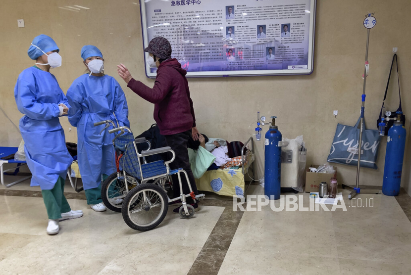  Pekerja medis berbicara  seorang wanita ketika menerima perawatan medis di lorong bangsal darurat di Beijing, Kamis, 19 Januari 2023. Sebanyak 6.364 warga China tewas karena terkena serangan Covid-19 dalam tujuh hari pada 20-26 Januari 2023. 