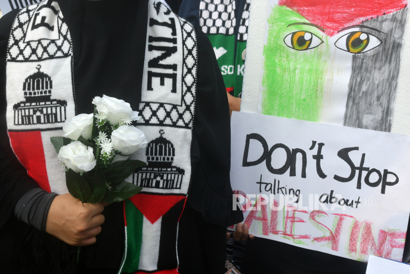 Peserta aksi membawa poster dan bunga saat aksi solidaritas Palestina di kawasan Tugu Kujang, Kota Bogor, Jawa Barat, Ahad (15/10/2023).
