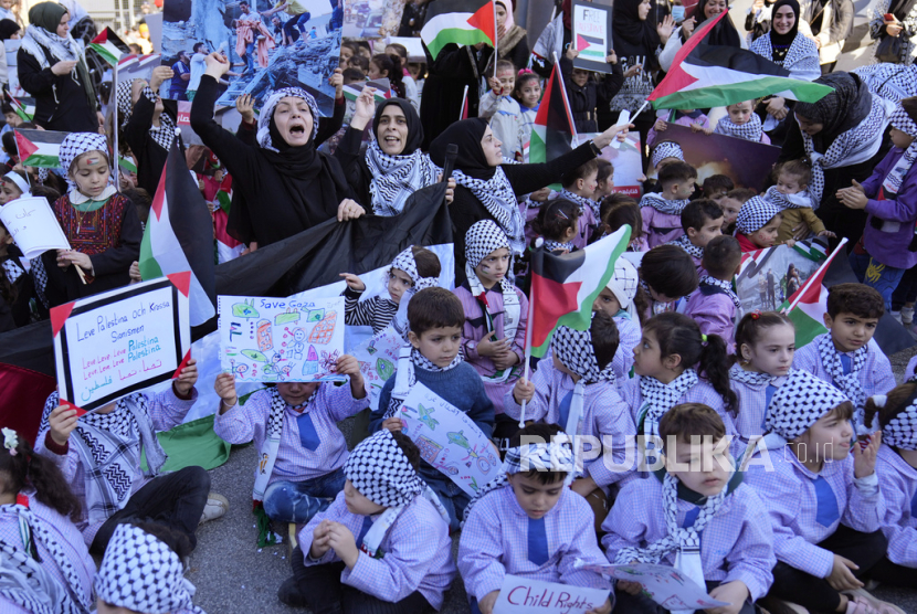 Guru siswa sekolah dasar Palestina, tengah, meneriakkan slogan-slogan saat menghadiri aksi duduk di luar kantor Delegasi Uni Eropa untuk Lebanon, untuk menunjukkan solidaritas mereka terhadap rakyat Palestina di Gaza, di Beirut, Lebanon, Kamis, (14/12/2023).