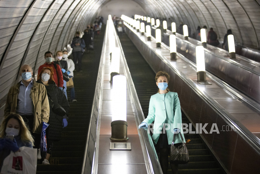 Orang-orang memakai masker dan sarung tangan untuk melindungi dari virus corona saat mereka turun dengan eskalator di kereta bawah tanah, Moskow, Rusia, Selasa (12/5). )