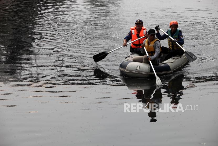 Petugas gabungan dari BPBD, Damkar dan KLHK menyusuri sungai saat pencarian buaya di Kawasan Grogol, Jakarta, Kamis (28/6).