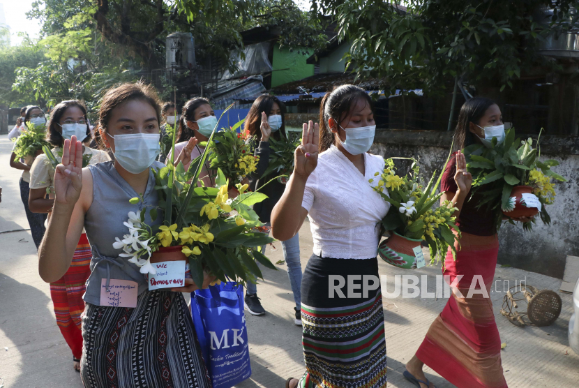 Pengunjuk rasa anti-kudeta berbaris membawa slogan di atas pot dengan bunga saat mereka menandai festival Thingyan pada hari Selasa 13 April 2021 di Yangon, Myanmar. 