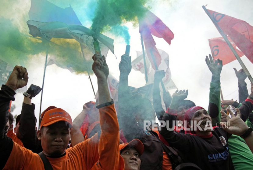  Pekerja menyalakan tongkat asap saat unjuk rasa May Day di Jakarta, Senin (1/5/2023). Pekerja dan aktivis di seluruh Asia menandai May Day dengan protes menyerukan gaji yang lebih tinggi dan kondisi kerja yang lebih baik, di antara tuntutan lainnya.