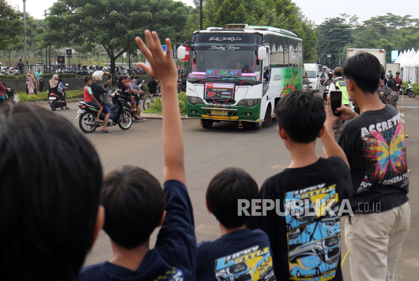 Sejumlah anak mendokumentasikan bus yang membunyikan klakson telolet saat melintas di Tapos , Depok Jawa Barat, Ahad (24/3/2024). Kementerian Perhubungan (Kemenhub) melarang penggunaan klakson telolet pada bus karena dianggap mengancam keselamatan jalan. 