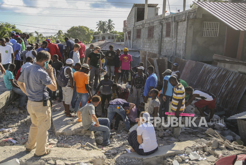  Orang-orang mencari korban selamat di puing-puing rumah yang hancur akibat gempa di Les Cayes, Haiti, Sabtu, 14 Agustus 2021. Gempa berkekuatan 7,2 melanda Haiti pada hari Sabtu, dengan pusat gempa sekitar 125 kilometer (78 mil) barat ibu kota Port-au-Prince, kata Survei Geologi AS.