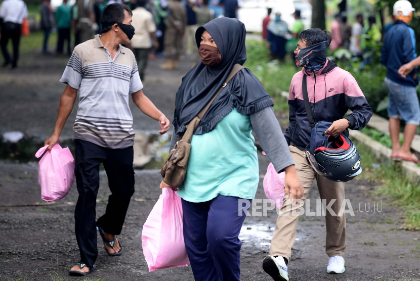 Warga membawa paket sembako usai dibagikan di gedung Baznas Kabupaten Bogor, Cibinong, Jabar, Senin (20/4). Ratusan warga rela mengantre dan tidak mepedulikan physical distancing untuk mendapatkan 5 kg beras dan 10 bungkus mie instan