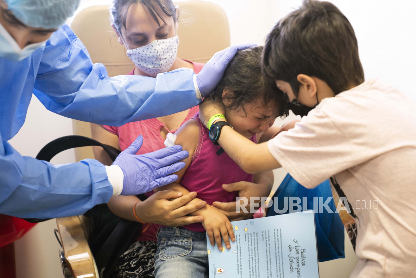 Seorang anak lelaki menghibur saudara perempuannya yang menjalani vaksinasi Covid-19 di Rumah Sakit Pereira Rossell di Montevideo, Uruguay, Rabu, 12 Januari 2022. Gejala omicron pada anak bisa berbeda dengan yang terjadi pada orang dewasa.