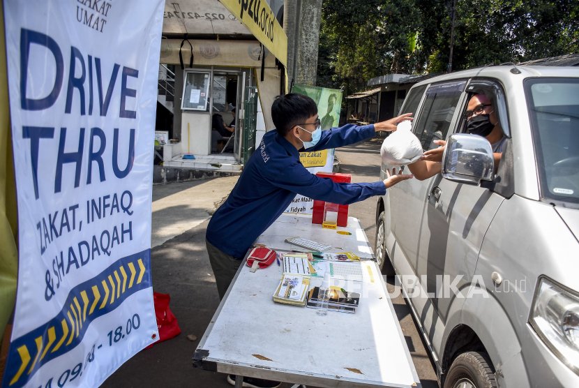 Petugas Amil Zakat menerima pembayaran zakat fitrah dari warga wajib zakat (muzaki) di depan Masjid Pimpinan Pusat (PP) Persis, Jalan Perintis Kemerdekaan, Kota Bandung, Senin (10/5). Pusat Zakat Umat Lembaga Zakat Persis membuka layanan pembayaran zakat fitrah menggunakan sistem drive thru atau layanan tanpa turun selama pandemi Covid-19 dengan memberlakukan protokol kesehatan guna mencegah penyebaran Covid-19. Foto: Republika/Abdan Syakura