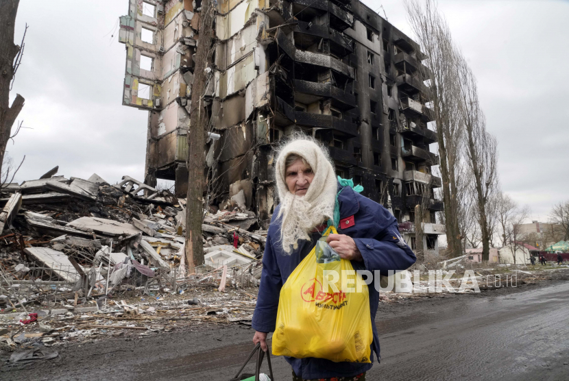 Seorang wanita tua berjalan di dekat gedung apartemen yang hancur dalam serangan Rusia di Borodyanka, Ukraina, Rabu, 6 April 2022.