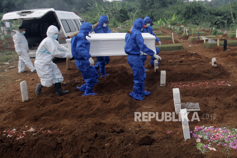 Petugas pemakaman membawa peti jenazah korban Covid-19 untuk dikuburkan  di TPU.