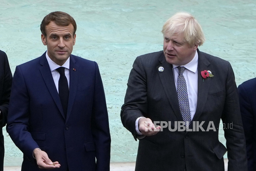 Presiden Prancis Emmanuel Macron, kiri, dan Perdana Menteri Inggris Boris Johnson bersiap untuk melempar koin ke dalam air di Air Mancur Trevi selama acara KTT G20 di Roma, Minggu, 31 Oktober 2021. 
