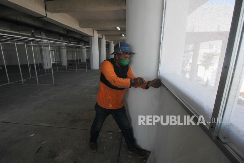 Pekerja membuat jendela di gedung lapangan tembak di kawasan Kedung Cowek, Surabaya, Jawa Timur, Ahad (4/7/2021). Pemkot Surabaya mengubah gedung lapangan tembak itu menjadi rumah sakit darurat yang berfungsi sebagai tempat isolasi mandiri bagi warga terpapar COVID-19. 