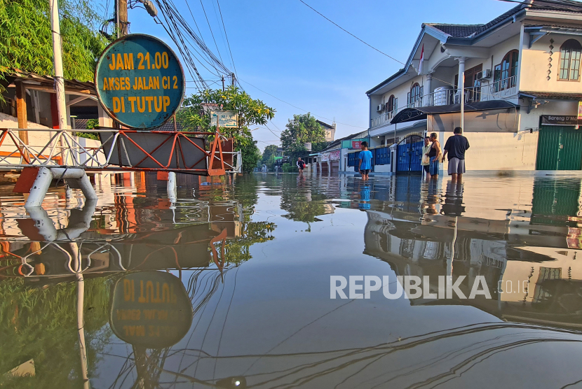 Sejumlah warga melintasi banjir yang merendam Perumahan Ciledug Indah, Ciledug, Tangerang, Banten, Ahad (11/9/2022). Banjir setinggi 50cm hingga 100cm yang merendam perumahan tersebut terjadi akibat meluapnya kali angke karena intensitas hujan yang cukup tinggi. 