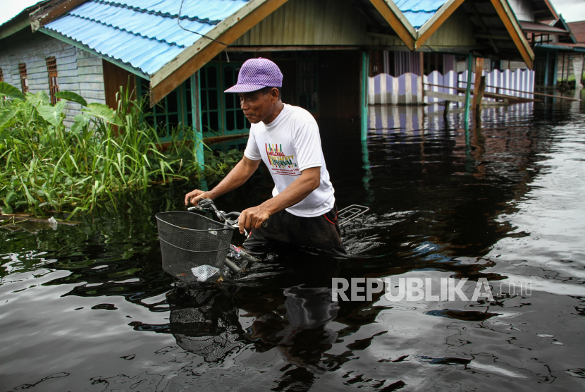 Seorang warga mengendarai sepeda melewati banjir di Jalan Anoi, Palangka Raya, Kalimantan Tengah, Ahad (10/3/2024). Curah hujan yang tinggi serta meluapnya Sungai Kahayan, Rungan, dan Sebangau mengakibatkan 16 kelurahan di empat kecamatan Kota Palangka Raya terendam banjir. 