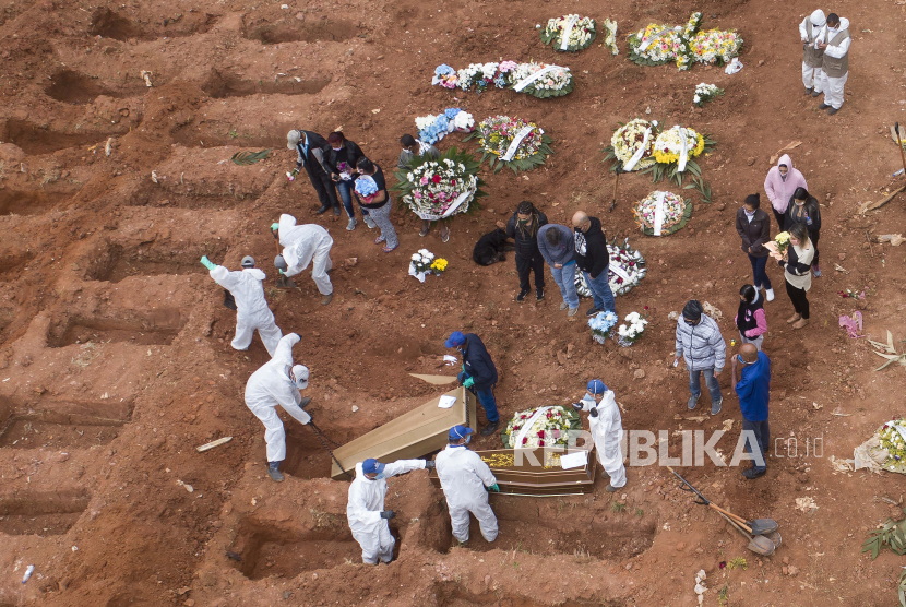  Pekerja pemakaman dalam pakaian pelindung mengubur korban coronavirus baru di pemakaman Vila Formosa di Sao Paulo, Brasil, Rabu, 15 Juli 2020. Brasil mendekati 2 juta kasus COVID-19 dan 75.000 kematian. 