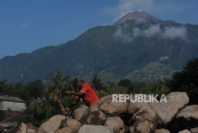 Pekerja beraktivitas memindahkan batu dengan latar belakang Gunung Merapi di Cepogo, Boyolali, Jawa Tengah.