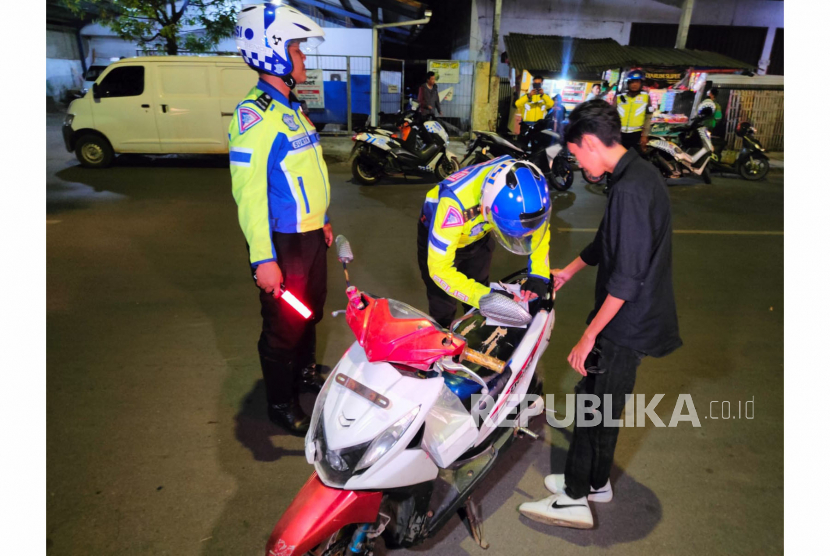 Ilustrasi polisi menindak dan menghukum pengendara sepeda motor berknalpot bising.